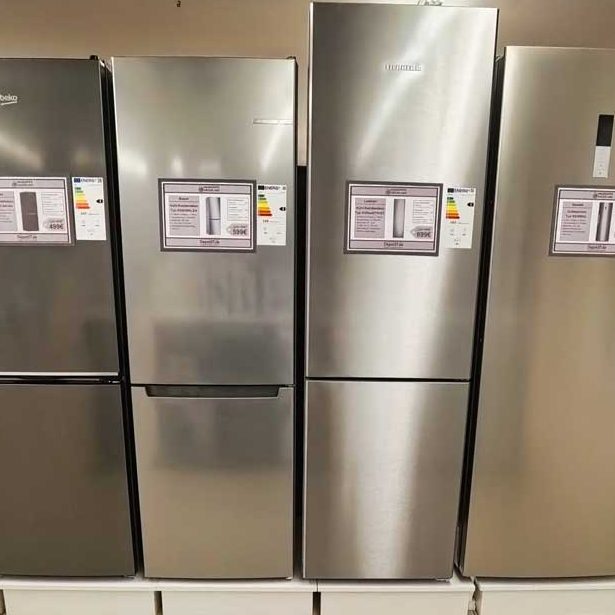 Vier silberne Kühlschränke nebeneinander in einem Geschäft, mit Preisschildern.