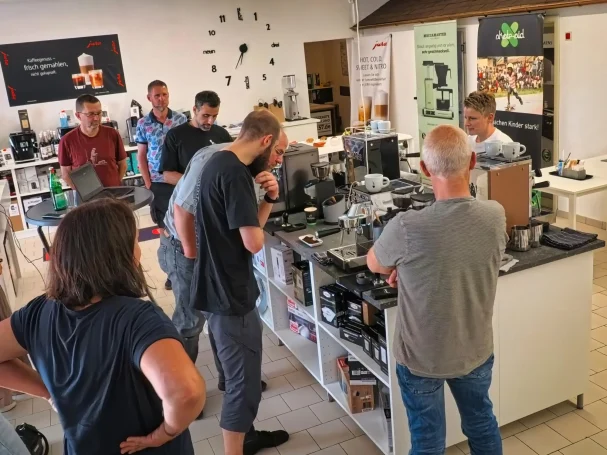 Live-Praxis an der Kücheninsel Kurs-Teilnehmer stehen um Kücheninsel bei Hausgeräte Siegerland für Siebträger-Praxis in Freudenberg