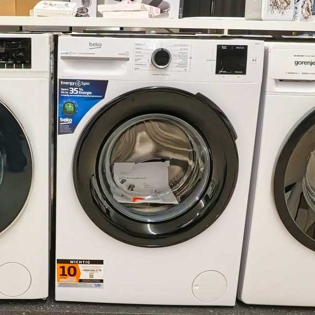 Drei weiße Waschmaschinen nebeneinander, mit sichtbarem Bullauge und Bedienfeldern.